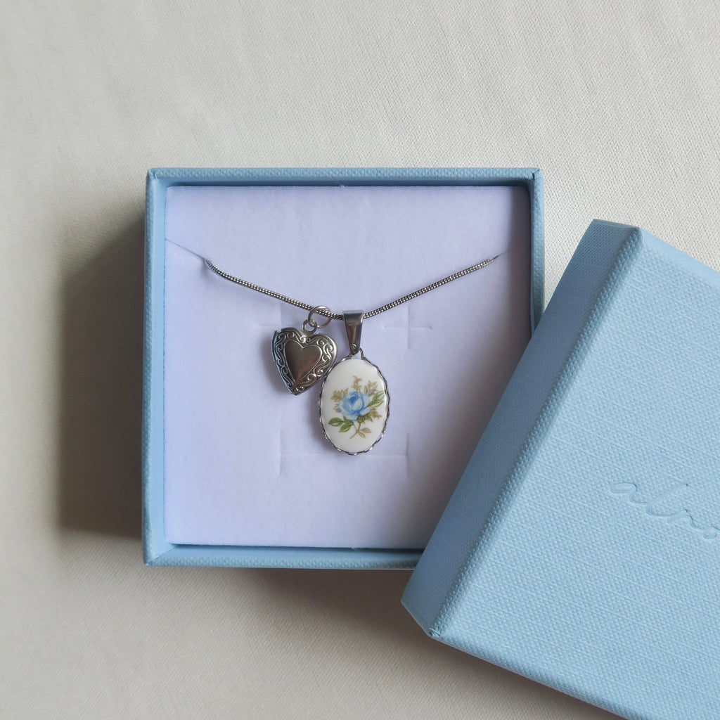 Necklace with heart-shaped pendant in a light blue jewelry box on a beige background