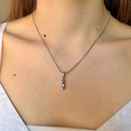 Necklace with a ballet pendant worn by a person.