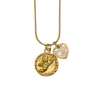 A gold-tone chain necklace with two charms: a textured, embossed round coin pendant with a cherub and a small heart-shaped charm with a smooth, milky-white inlay, shown against a plain white background.